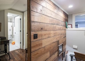 A room with wooden paneling on the walls, a door leading to another room, and a small window. - Location, Location, Location! (Oxford)