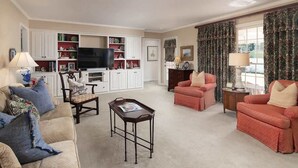 Ein Wohnzimmer mit Fernseher, zwei Sofas, einem Couchtisch und einem Bücherregal.