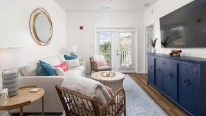Un salon comprenant un canapé, des fauteuils, une table basse, un meuble et un téléviseur.