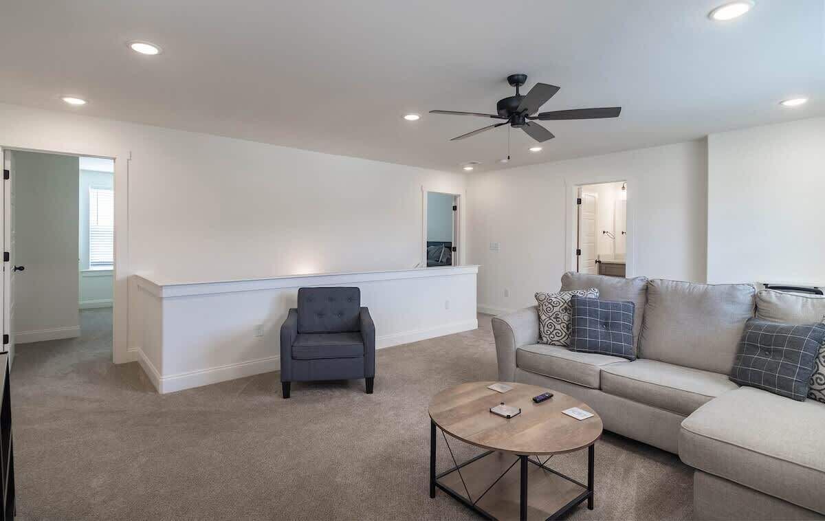 Un salon comprenant un canapé, un fauteuil, une table basse et un ventilateur de plafond.