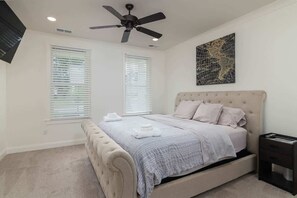 A bedroom with a bed, two windows, a ceiling fan, and a wall-mounted artwork. - Nuttall Oak Retreat (Oxford)