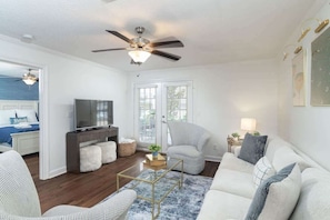 A living room with a ceiling fan, a TV, a sofa, a chair, and a coffee table.