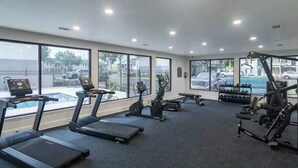 Une salle de sport équipée de tapis de course, de vélos d’appartement et d’appareils de musculation.