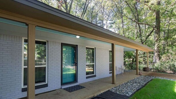 Una casa moderna con un porche cubierto, una puerta principal y un pequeño jardín.