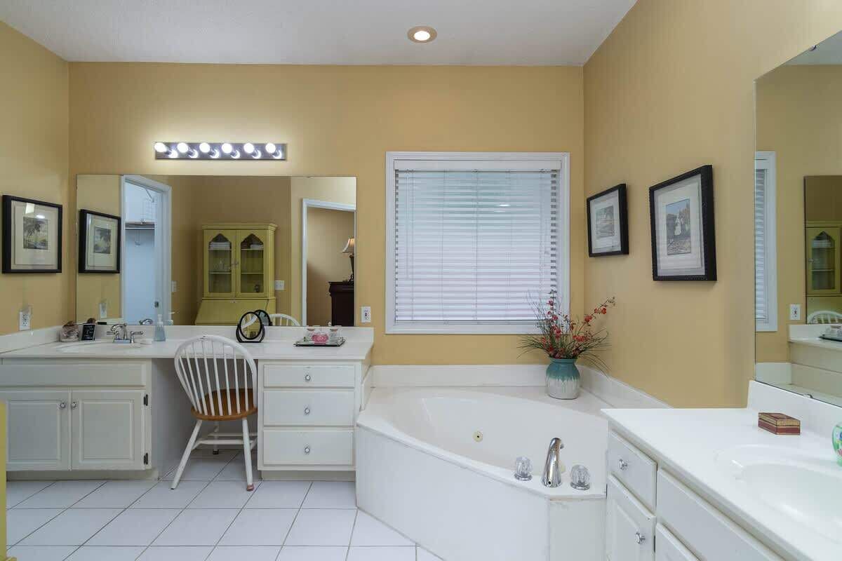 Une salle de bain avec une baignoire, un meuble-lavabo et une chaise.