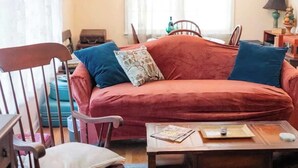 Ein gemütliches Wohnzimmer mit einem roten Sofa, einem Holzschaukelstuhl, einem Couchtisch und einer Pendelleuchte.
