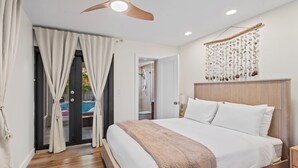 Ein Schlafzimmer mit Bett, Holz-Kopfteil, Deckenventilator und einer Wanddekoration.