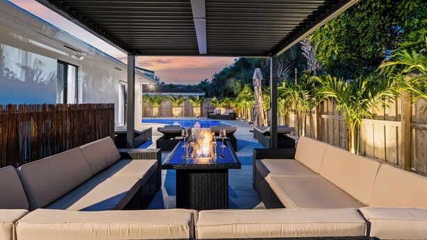 Eine überdachte Terrasse im Freien mit Pool, Liegebereich und Feuerstelle.
