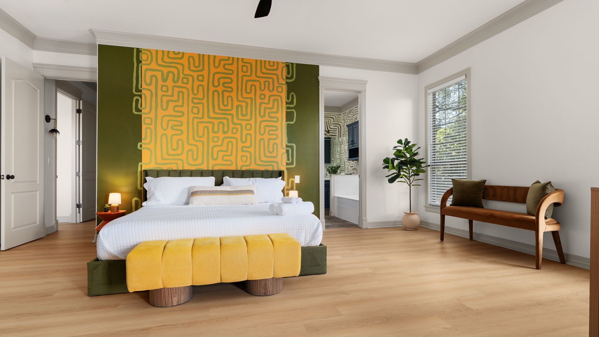 Une chambre spacieuse avec un grand lit, un banc en bois et un mur d’accent de couleur verte.