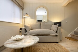 Ein modernes Wohnzimmer mit einer Couch, einem runden Couchtisch, einer Lampe und einem Spiegel an der Wand.