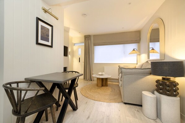 A modern room with a dining table, chairs, a sofa, a round coffee table, a lamp, and a mirror. - Argyl | Central Old Town Mews Home w/ Parking (Edinburgh)