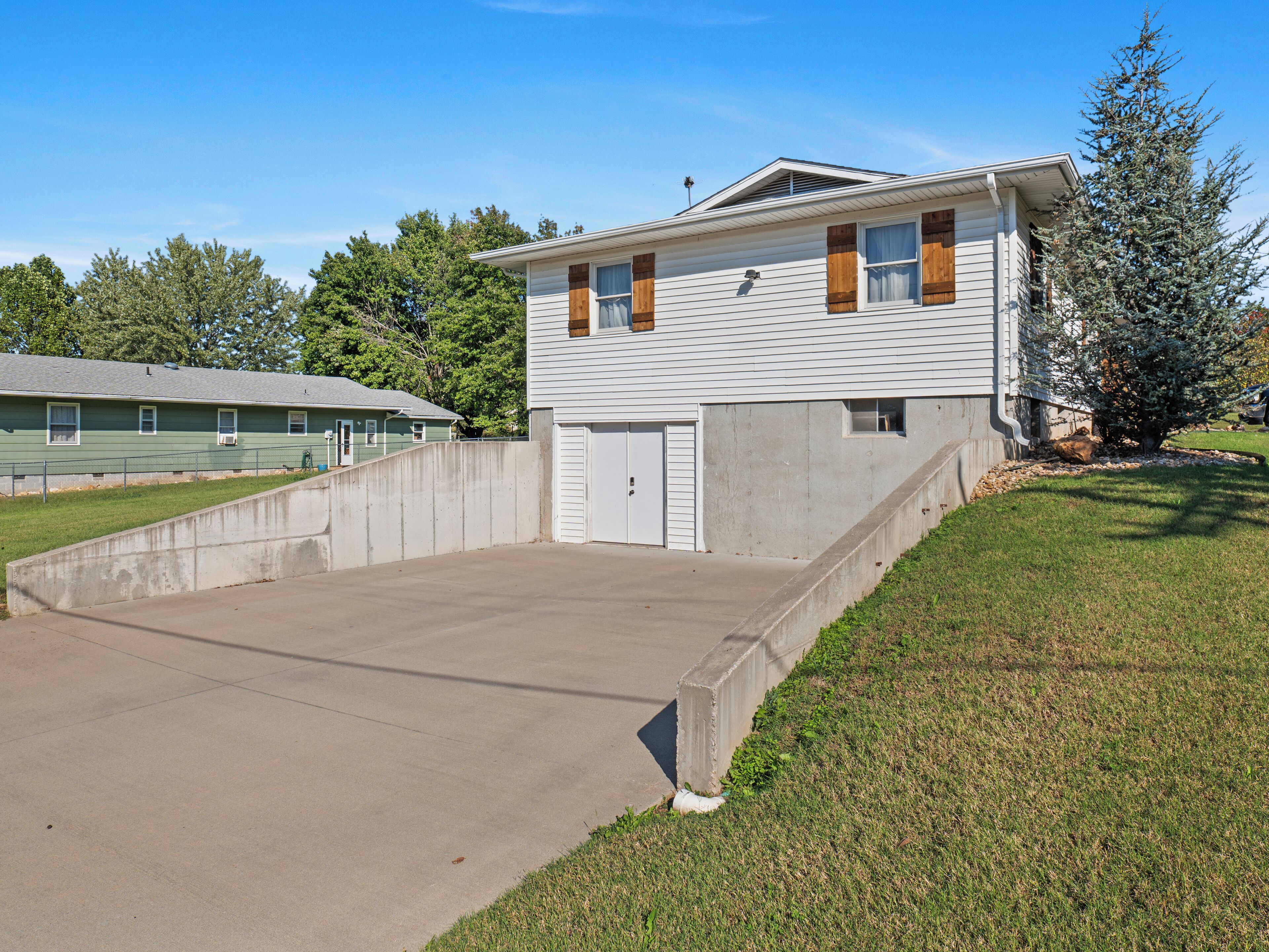 Un bâtiment à deux étages avec un garage, une allée en béton et une petite pelouse.