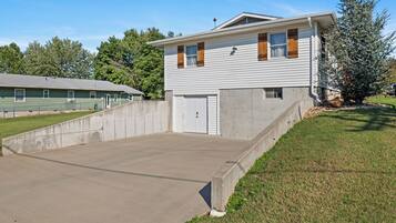 Un bâtiment à deux étages avec un garage, une allée en béton et une petite pelouse.
