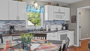 A modern kitchen with white cabinets, a granite countertop, a built-in microwave, and a ceiling fan.