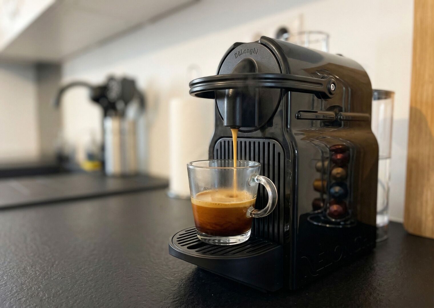 A coffee machine dispensing coffee into a clear glass cup.