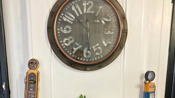 A wall clock with a vintage design, a garage service emblem, and a small potted plant.