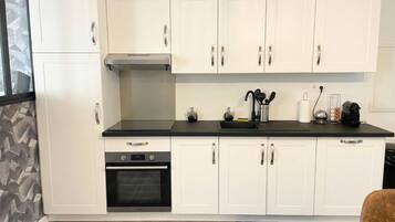 A modern kitchen with white cabinets, a black countertop, stainless steel appliances, and a built-in oven.
