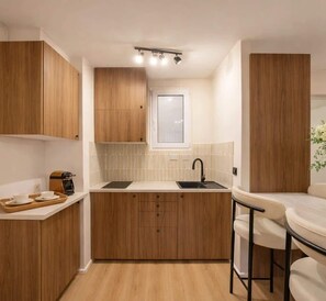 Eine kompakte Küche mit Holzausbau, einer weißen Arbeitsplatte, einem Spülbecken und einem kleinen Essbereich mit einem Stuhl.