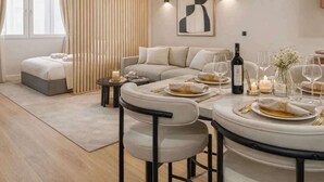 A modern living room with a sofa, a dining table set for a meal, and a large abstract painting on the wall. - Montmartre studio with elevator access (Paris)