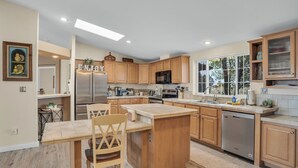Una cucina moderna con mobili in legno, un frigorifero in acciaio inossidabile e una grande isola con posti a sedere.