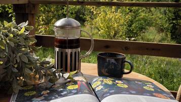 Un libro abierto sobre una mesa de madera, con una cafetera y una taza cerca.