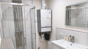 A modern bathroom with a glass-enclosed shower, a white sink with a mirror, and a toilet. - Home Sweet Home - Feel-good vacation home (Cuxhaven)