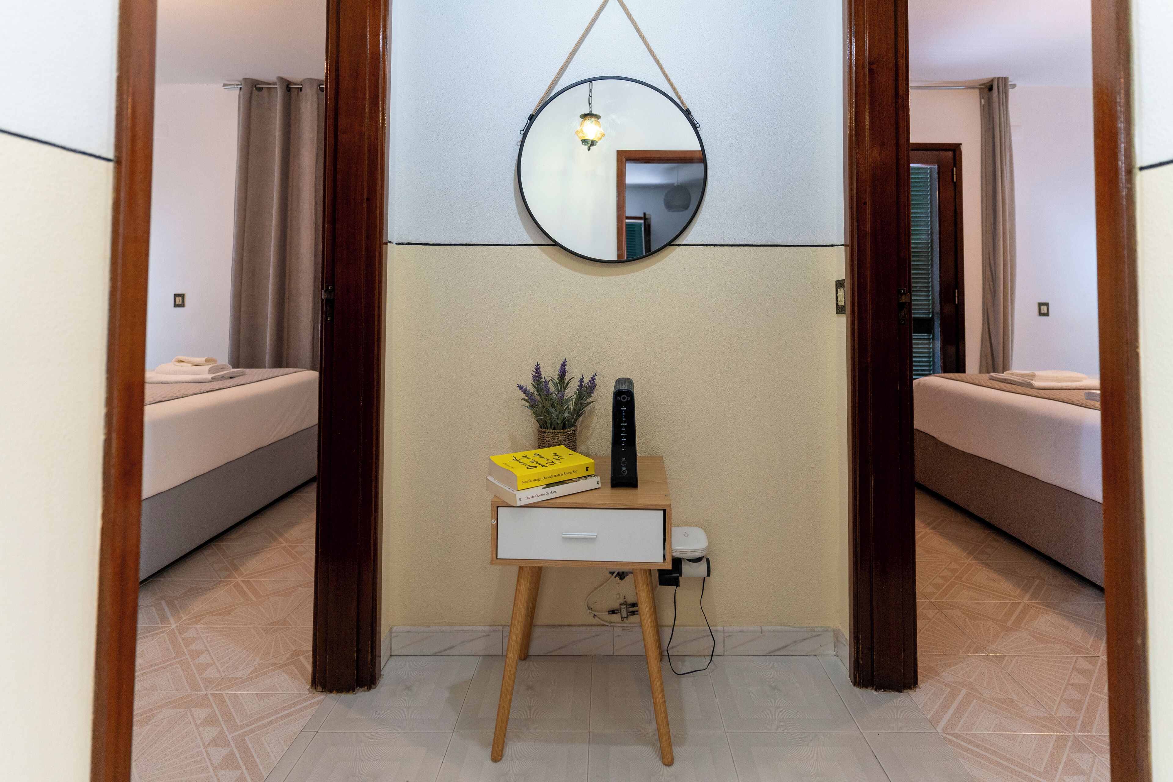 A bedroom with a bed, a bedside table with a lamp, and a mirror on the wall.