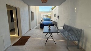 A narrow corridor with a bench, a table with a potted plant, and a car parked outside. - African House Peschici (Peschici)