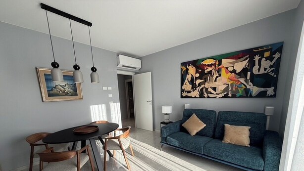 A modern living room with a blue sofa, a dining table with chairs, and a large abstract painting on the wall. - African House Peschici (Peschici)
