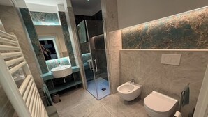 A modern bathroom with a glass-enclosed shower, a bidet, and a sink. - African House Peschici (Peschici)