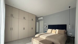 A modern bedroom with a large bed, a bench, and a wardrobe. - African House Peschici (Peschici)