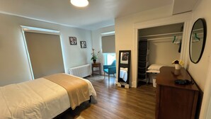 A bedroom with a bed, a dresser, a mirror, and a closet. - Wolfville DT • Modern 3BR • 1.5 Bath Suite Seaview (Wolfville)