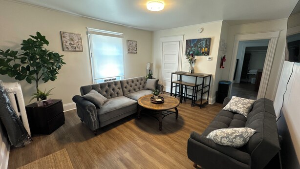 A living room with a sectional sofa, a round coffee table, and a potted plant. - Wolfville DT • Modern 3BR • 1.5 Bath Suite Seaview (Wolfville)