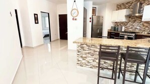 A modern kitchen with a central island, stainless steel appliances, and a tiled backsplash. - Family escape with pool & beach acces (Puerto Aventuras)