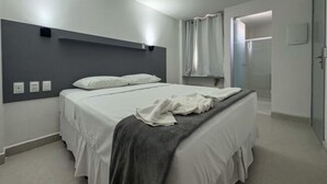 Et moderne soveværelse med en stor seng, en sengegavl og et bruseområde.