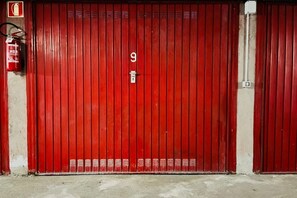 En röd garagedörr med siffran 9, en brandsläckare och en elcentral.