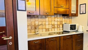 Una cocina con armarios de madera, encimera blanca, fregadero y microondas.