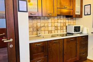 Eine Küche mit Holzausstattung, einer weißen Arbeitsplatte, einem Spülbecken und einer Mikrowelle.
