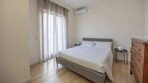 Een slaapkamer met een bed, een kaptafel, een nachtkastje en een airconditioning.