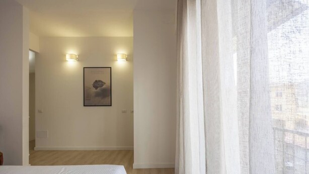 Een hotelkamer met een bed, een ingelijst schilderij aan de muur en een raam met gordijnen.