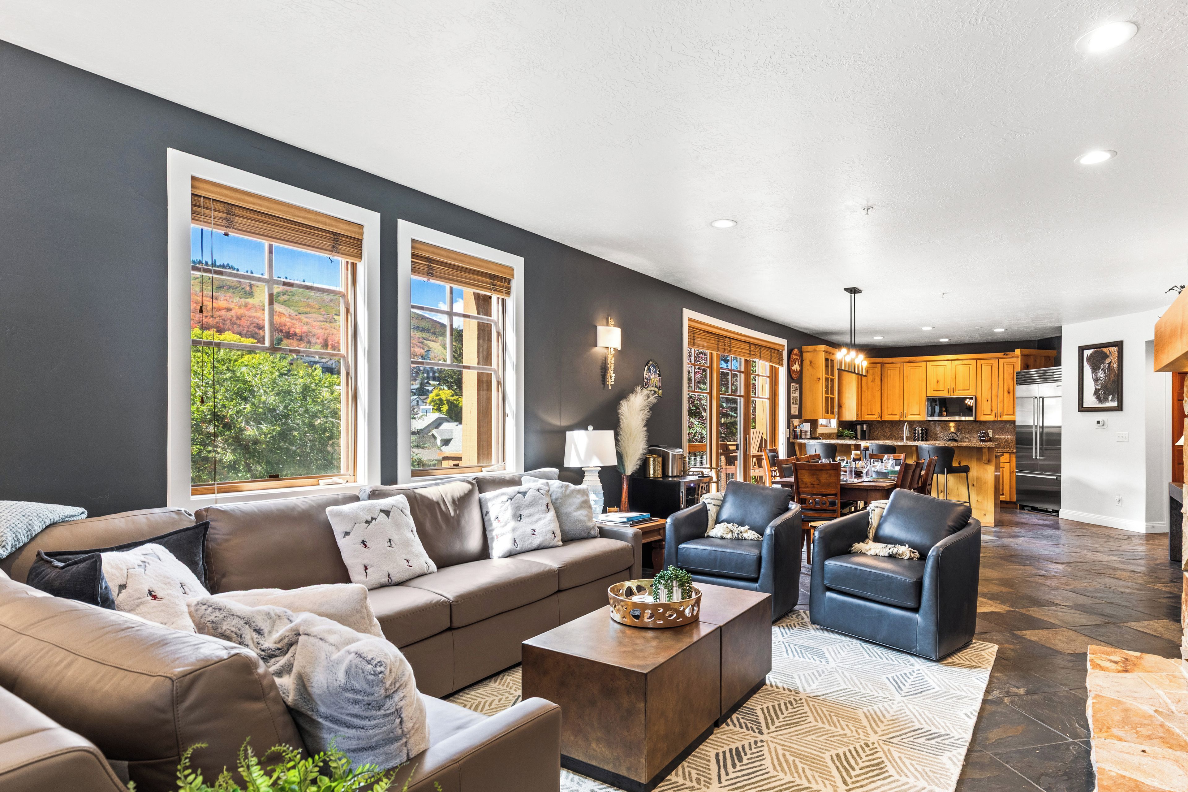 A spacious living area with a sofa, chairs, a coffee table, and a view of the kitchen.