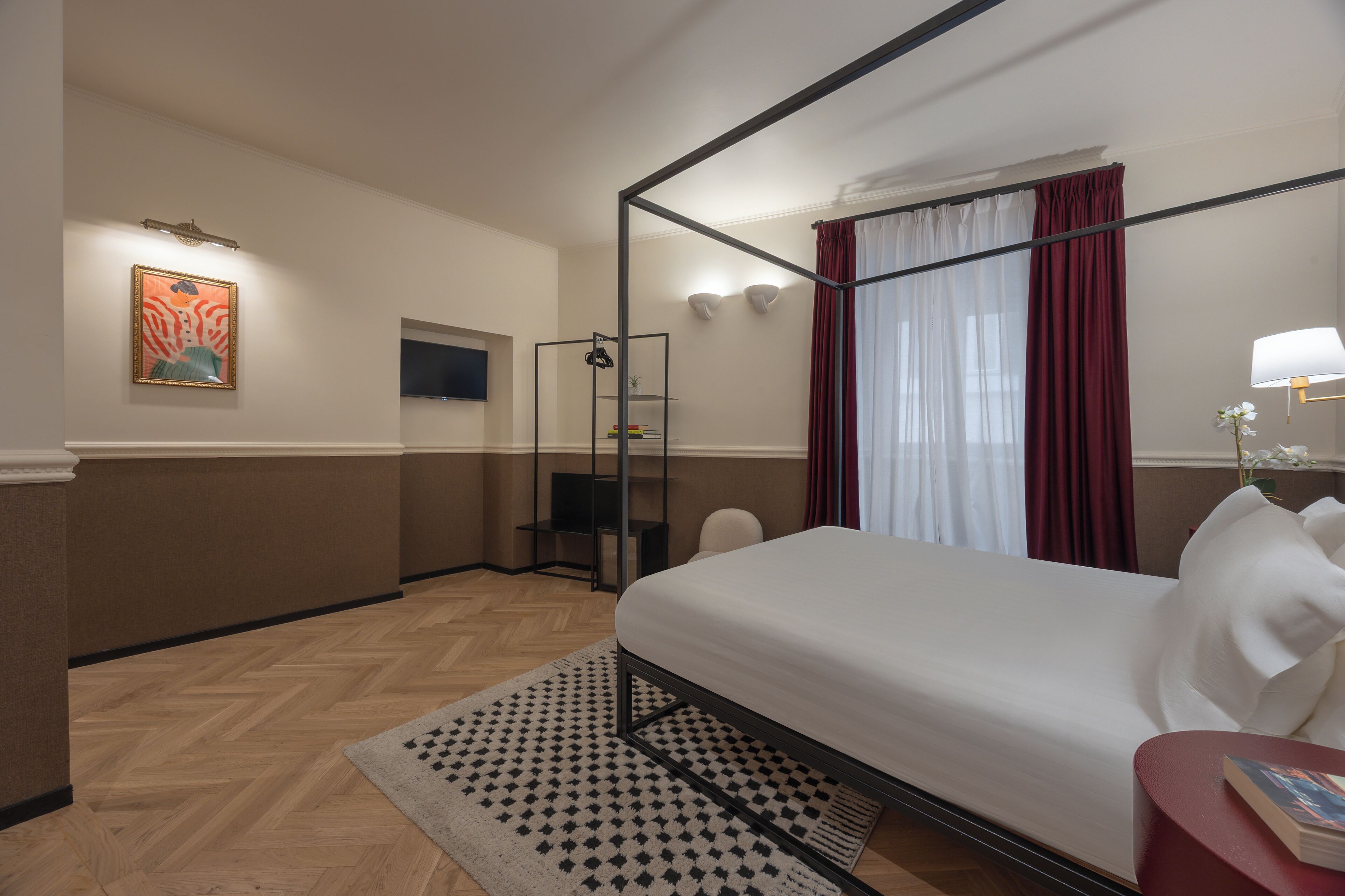A hotel room with a four-poster bed, a shower, a seating area, and a painting on the wall.
