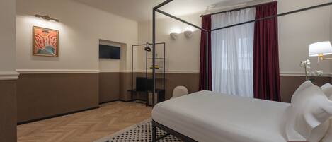 A hotel room with a four-poster bed, a shower, a seating area, and a painting on the wall.