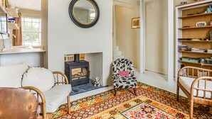 Una sala de estar acogedora con chimenea, un tapete estampado y una estantería.