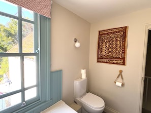 A bathroom with a toilet, a window with a view of the outside, and a wall-mounted towel rack. - 8 Mariners Terrace (Chichester)