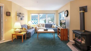 A cozy living room with a sofa, coffee table, and a fireplace. - The Haven at Blueberry Hill - Mount Washington ski-in/out (Comox-Strathcona C)