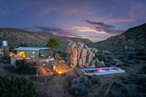 Una casa in stile desertico con patio, una grande formazione rocciosa e una piscina.