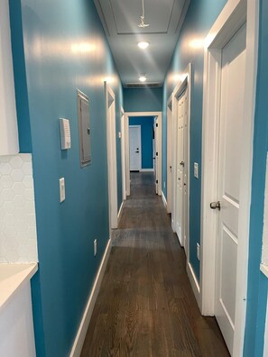 Un corridoio con pareti blu, porte bianche e pavimento in legno.