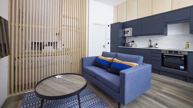 A modern kitchen with dark cabinetry, a built-in oven, and a microwave. - Argyl | Abbey Gate: Studio 11 (Edinburgh)