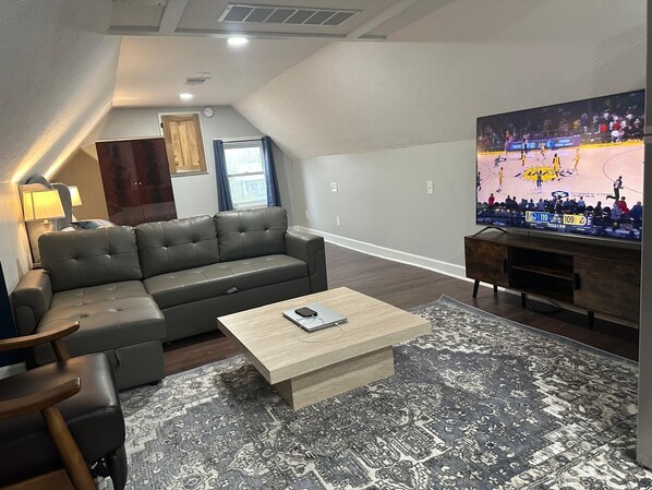 Uma sala de estar moderna com um sofá modular, uma mesa de centro e uma televisão de tela plana grande fixada na parede.